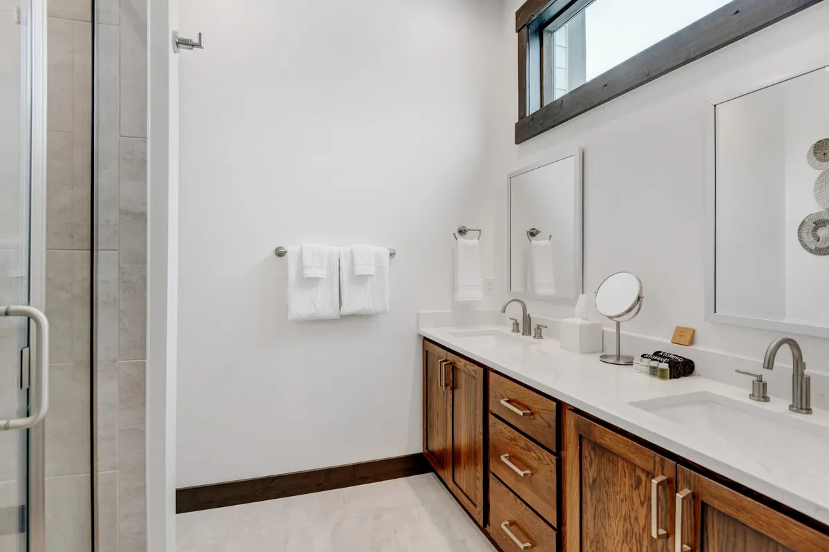 A modern bathroom with a double vanity, mirrored cabinets, and a spacious shower area. The setting is bright and refreshing, suggesting spa-quality toiletries and a space for self-care routines.