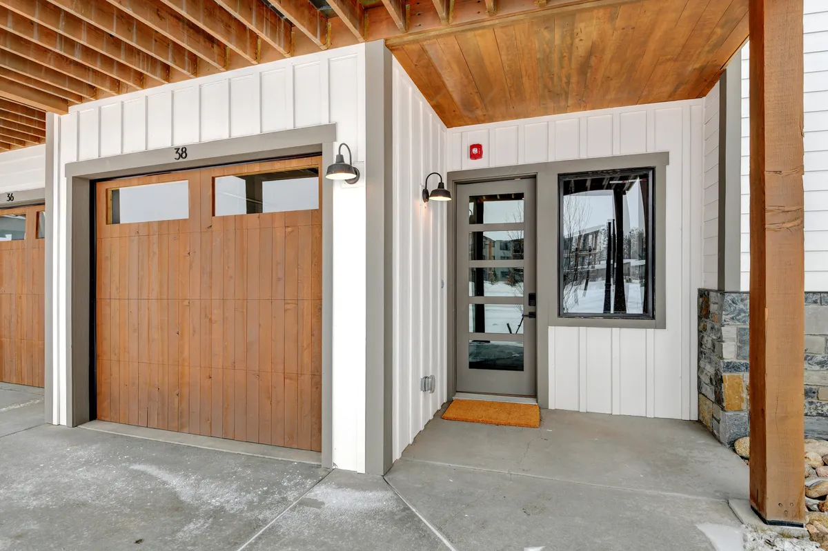 This exterior image focuses on the wooden garage door and entryway with stone accents, suggesting a heated and welcoming garage space. The entryway looks cozy and functional, ideal after a day in the mountains.
