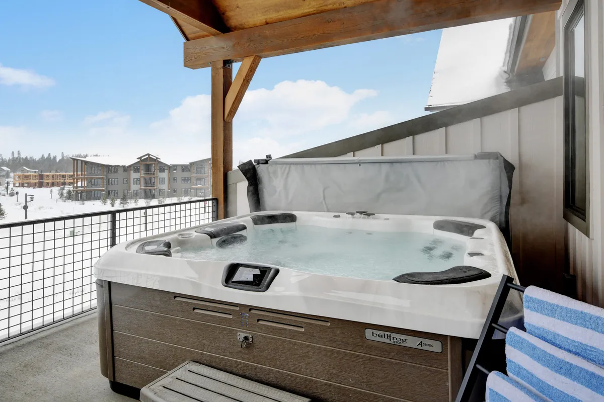 A serene exterior view featuring a private hot tub overlooking a snow-covered landscape and majestic mountain views. This inviting outdoor space is perfect for relaxing and sharing stories after a day of adventure.