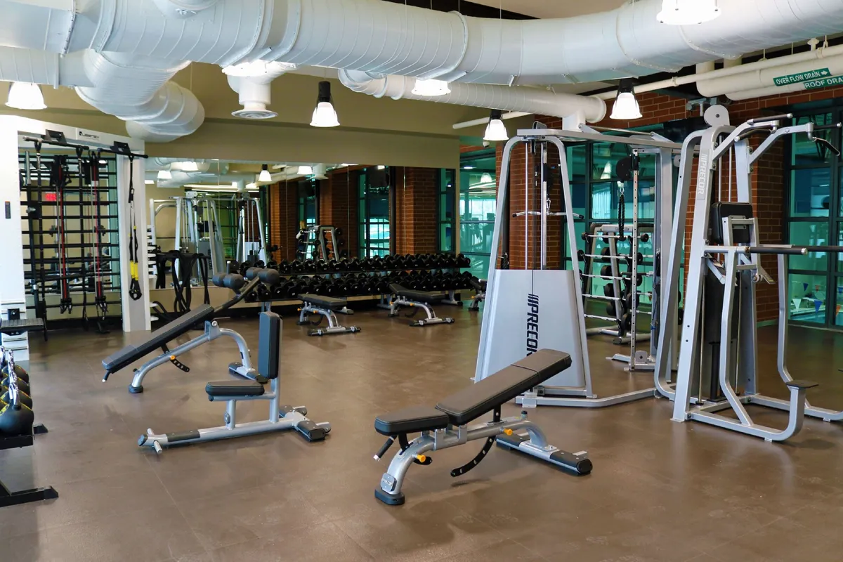 A home gym setup is pictured with weightlifting equipment, exercise benches, and mirrored walls, creating an active and motivating environment for personal fitness and wellness routines.